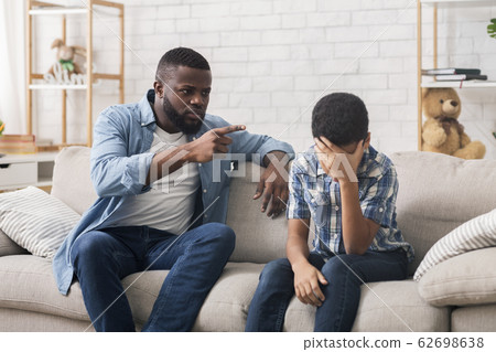 Angry black father scolding stubborn son for bad behavior at home 62698638