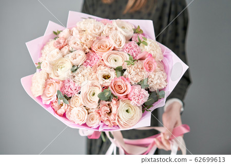 European floral shop. Beautiful bouquet of mixed flowers in womans hands. the work of the florist at a flower shop. Delivery fresh cut flower. 62699613