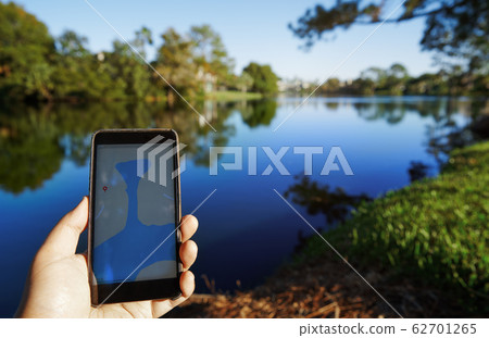Man using mobile map app next to the lake Man using mobile map app next to the lake 62701265