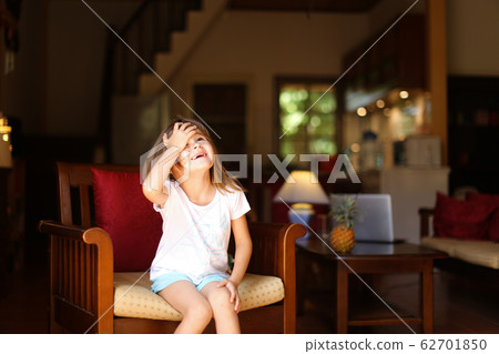 Little cute girl sitting in wooden chair in living room. 62701850