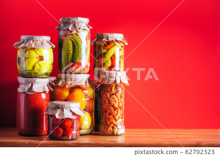 Сucumber, squash and tomatoes pickling and canning into glass jars. Ingredients for vegetables preserving. Healthy fermented food concept. Harvest storing Сucumber, squash and tomatoes pickling and canning into glass jars. Ingredients for vegetables preserving. Healthy fermented food concept. Harvest storing 62702323