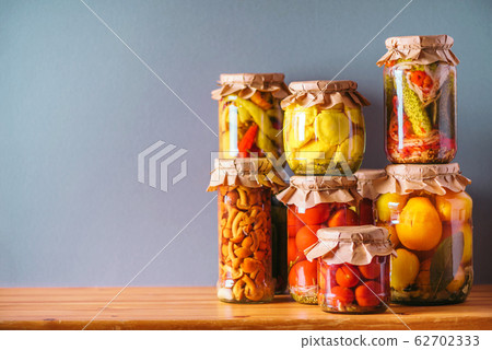 Preserved and fermented food in glass jars. Fermented food. Autumn canning. Сucumber, squash and tomatoes pickling and canning into glass jars. Preserved and fermented food in glass jars. Fermented food. Autumn canning. Сucumber, squash and tomatoes pickling and canning into glass jars. 62702333