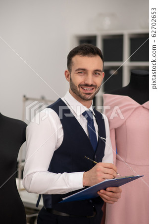 Male tailor standing next to dummy 