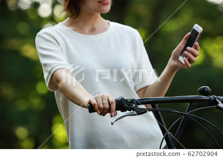 騎自行車的婦女，當操作智能手機時 62702904