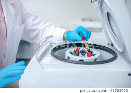 Close up of human hand putting the test tube to centrifuge 62703760