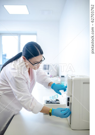 Technician in blue gloves switching on the centrifuge 62703762