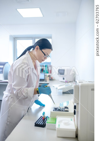 Technician in blue gloves pouring blood sample into the test tube 62703765