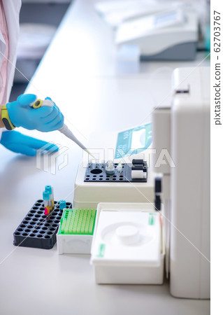 Technician in blue gloves holding pipette in hand 62703767