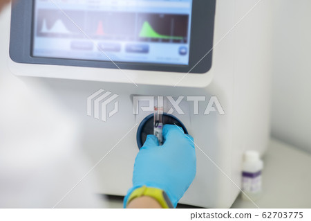 Technician in blue gloves switching on hematological analyzer Technician in blue gloves switching on hematological analyzer 62703775