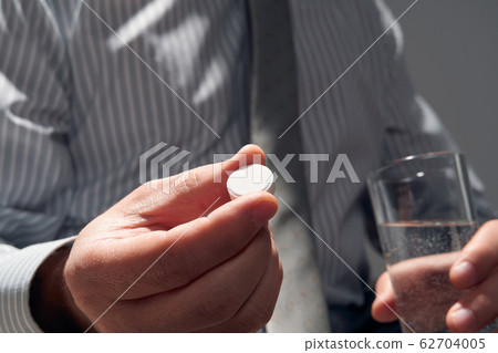 businessman with a pill, hands close view - 62704005