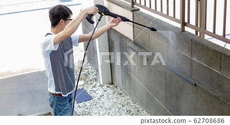 A man cleaning with a high pressure washer 62708686