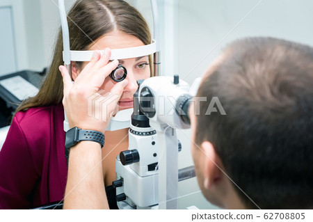 Attentive optometrist examining female patient in ophthalmology clinic 62708805