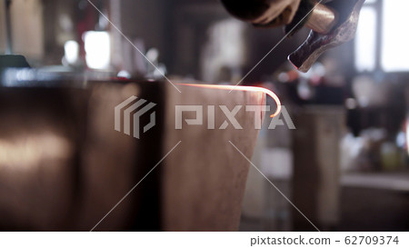Blacksmith torque the longer piece of metal in a spiral 62709374