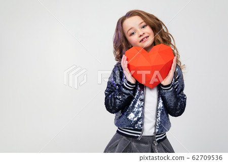 close-up of a happy stylish caucasian girl holding a red paper heart for valentines day on a white close-up of a happy stylish caucasian girl holding a red paper heart for valentines day on a white 62709536