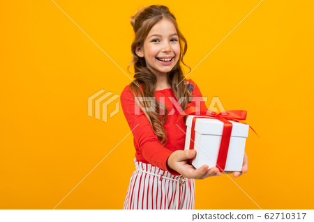 smiling beautiful girl holds out a box with a birthday present on a yellow background smiling beautiful girl holds out a box with a birthday present on a yellow background 62710317