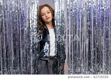 charming teen girl in a stylish outfit at a party on the background of tinsel 62710320