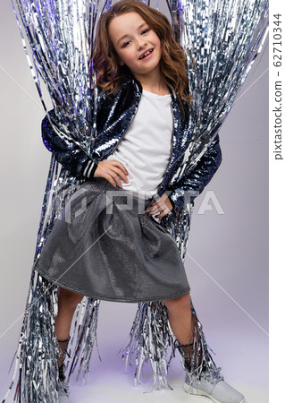 full-length photo of a stylish teenage girl in a festive dress among suspended tinsel in the form of 62710344