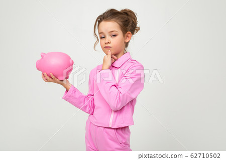 finance. portrait of a girl in a pink suit holding a money jar on a white background with copy space 62710502