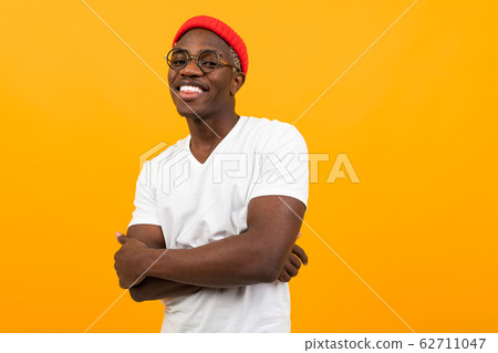 attractive african guy in a white t-shirt on a yellow background with copy space 62711047