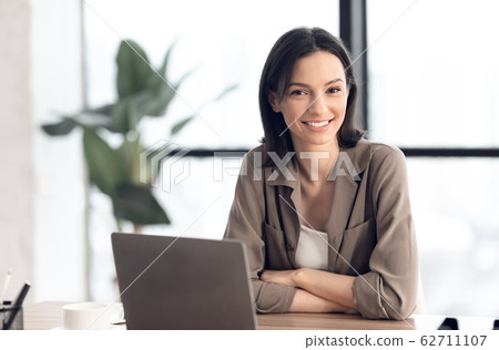 Happy young manager smiling at camera in her office Happy young manager smiling at camera in her office 62711107
