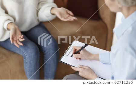 Psychologist Talking With Patient Taking Notes Sitting In Office, Cropped Psychologist Talking With Patient Taking Notes Sitting In Office, Cropped 62711250