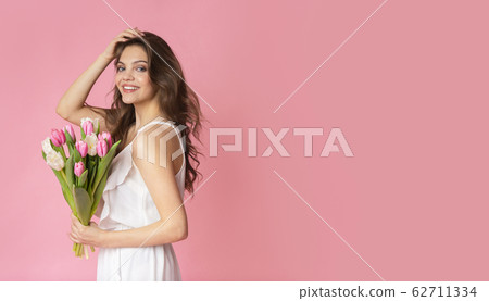 Romantic beautiful woman holding bunch of tulips and touching her hair Romantic beautiful woman holding bunch of tulips and touching her hair 62711334