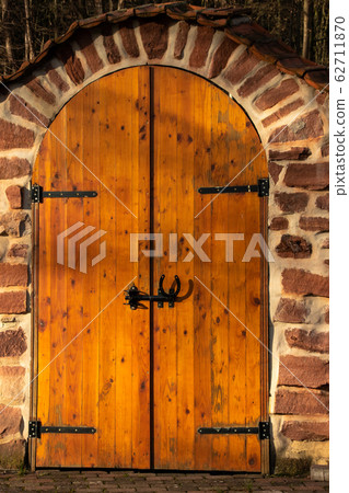 Wooden gate with stone arch 62711870