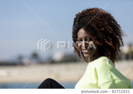 Beautiful afro american woman sitting on shore in Beautiful afro american woman sitting on shore in 62712031