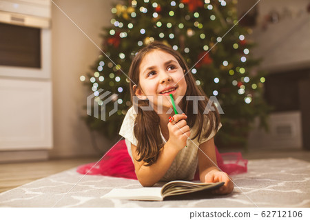 Happy girl dreaming about best gift for Christmas 62712106