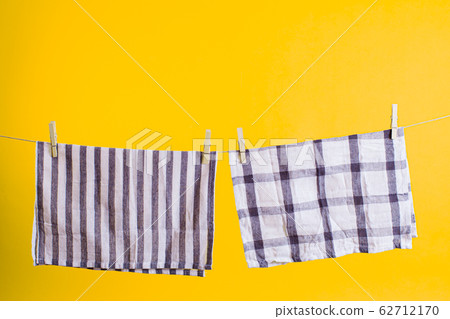 Eco friendly household items. Washed towels with wooden clothespins hanging on the rope Eco friendly household items. Washed towels with wooden clothespins hanging on the rope 62712170