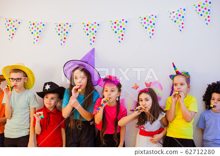 Happy joyful children celebrate birthday and wear funny party caps. Cute kids blowing whistles 62712280