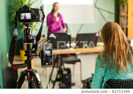 Professional camera is recording seminar with optional accessory. Woman making presentation, lection or meeting. Professional camera is recording seminar with optional accessory. Woman making presentation, lection or meeting. 62712360