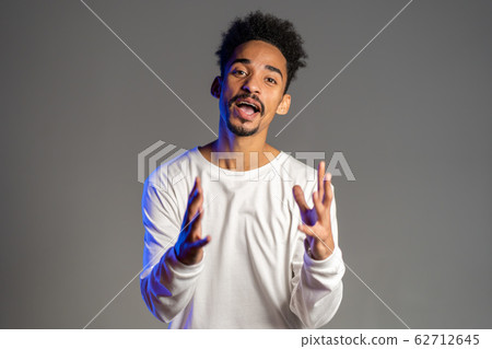 Young energetic african american man in white wear smiling and dancing in good mood on brown background. Young energetic african american man in white wear smiling and dancing in good mood on brown background. 62712645