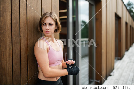 A young sportswoman standing outdoors on terrace, resting. A young sportswoman standing outdoors on terrace, resting. 62713132