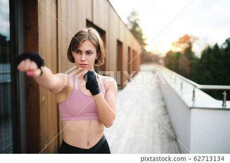 A young woman practising karate outdoors on terrace. A young woman practising karate outdoors on terrace. 62713134