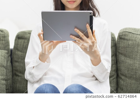 Woman operating a tablet in the living room Woman operating a tablet in the living room 62714864