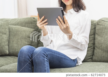 Woman operating a tablet in the living room Woman operating a tablet in the living room 62714873