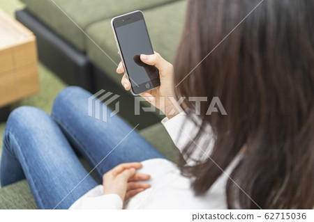 坐長沙發和操作智能手機的婦女 62715036