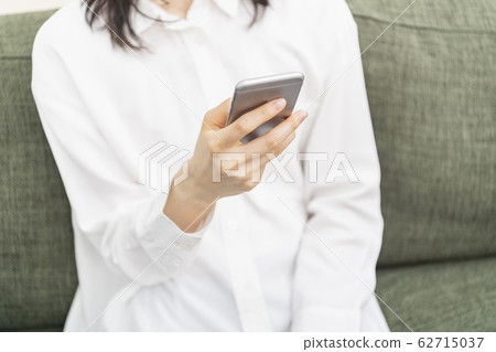 坐長沙發和操作智能手機的婦女 62715037