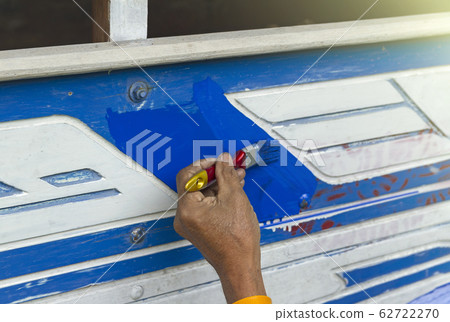 hand holding a brush applying varnish paint on a car wooden surface 62722270