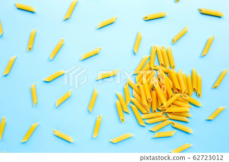 Uncooked penne pasta isolated on blue background. Uncooked penne pasta isolated on blue background. 62723012