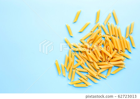 Uncooked penne pasta isolated on blue background. 62723013