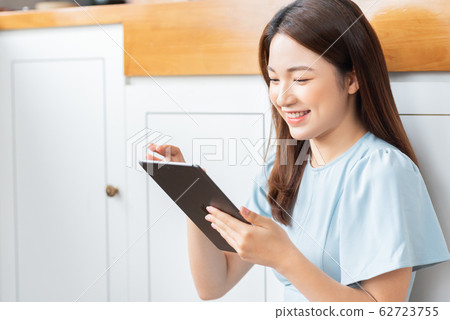 A beauty woman using tablet in the kitchen A beauty woman using tablet in the kitchen 62723755