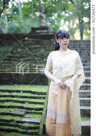 Portrait of Thai female with traditional Thai dress with temple background 62726472