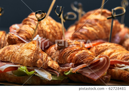 A large set of many croissants with different fillings laid out on a table on a gray background. Seth fast food. Gray background, copy space. 62728481