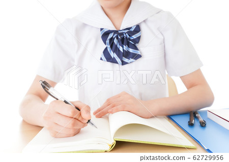 Female student in uniform studying at desk Female student in uniform studying at desk 62729956