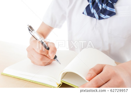 Female student in uniform studying at desk Female student in uniform studying at desk 62729957