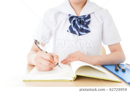 Female student in uniform studying at desk Female student in uniform studying at desk 62729959