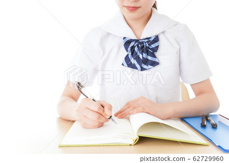 Female student in uniform studying at desk Female student in uniform studying at desk 62729960