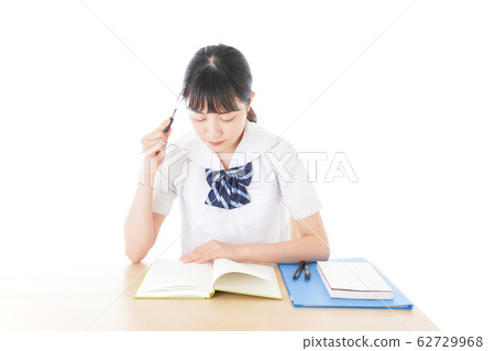 Female student in uniform studying at desk Female student in uniform studying at desk 62729968